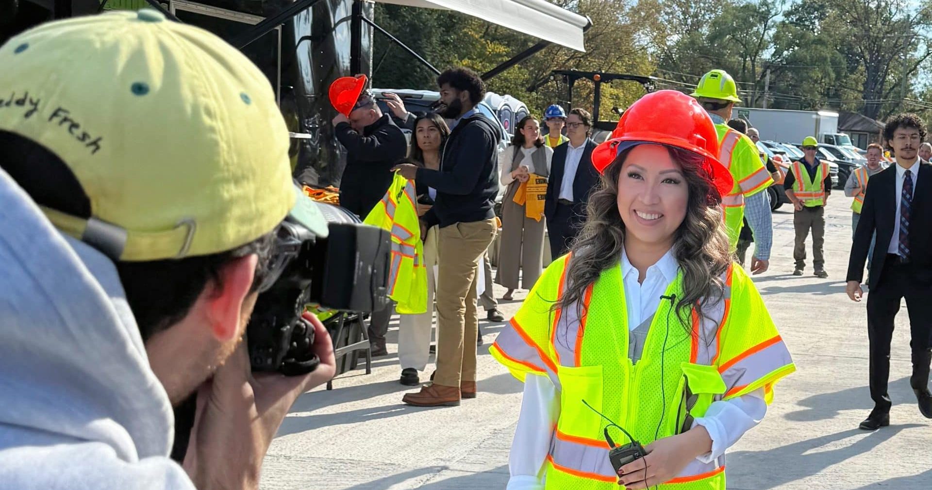 State Representative Mai Xiong in a construction vest and hardhat posing for a photographer.