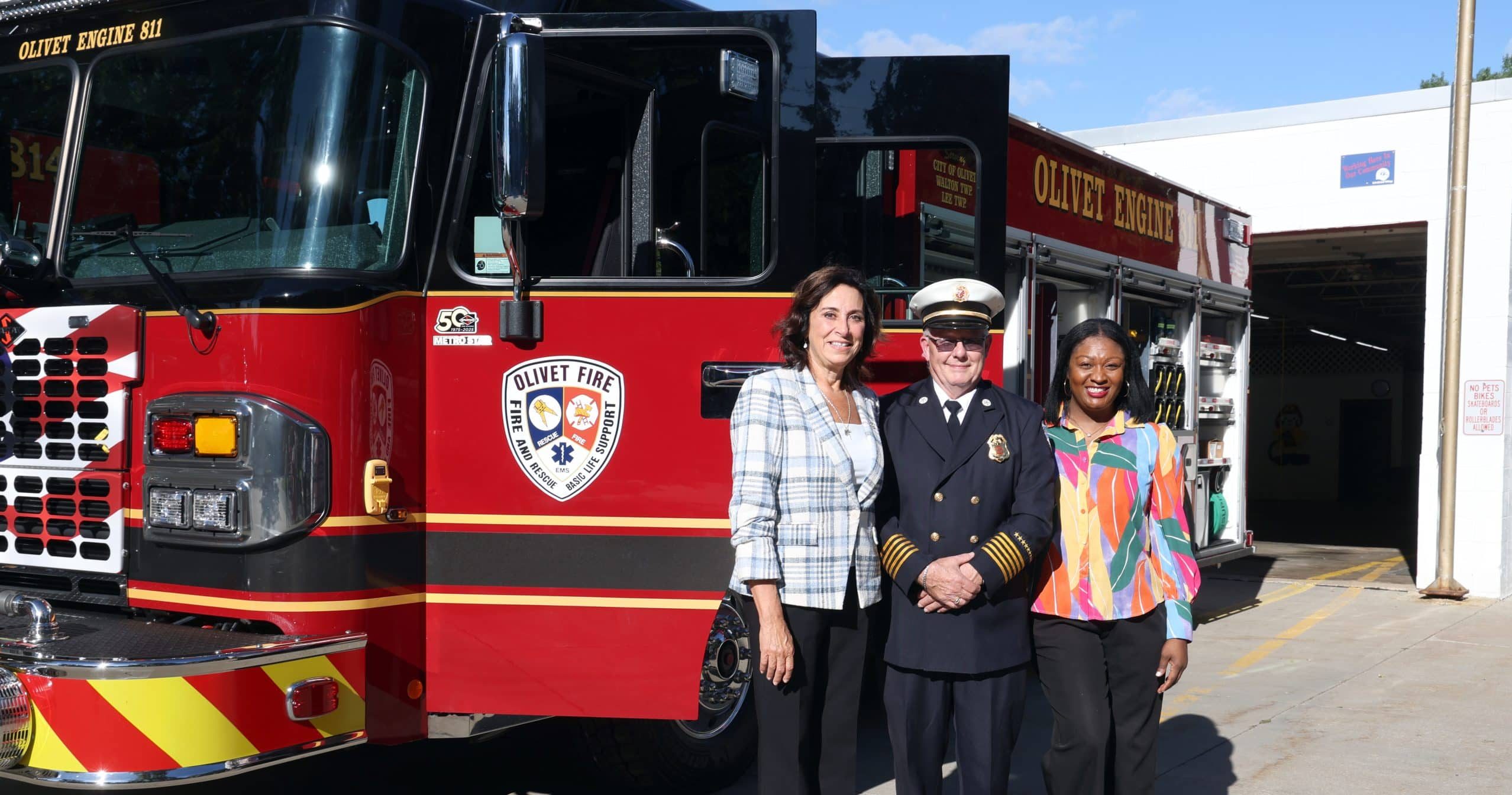 State Representative Angela Witwer, Olivet Fire Chief John Collins and state Senator Sarah Anthony stand for a photo together in front of the brand-new Olivet fire engine.