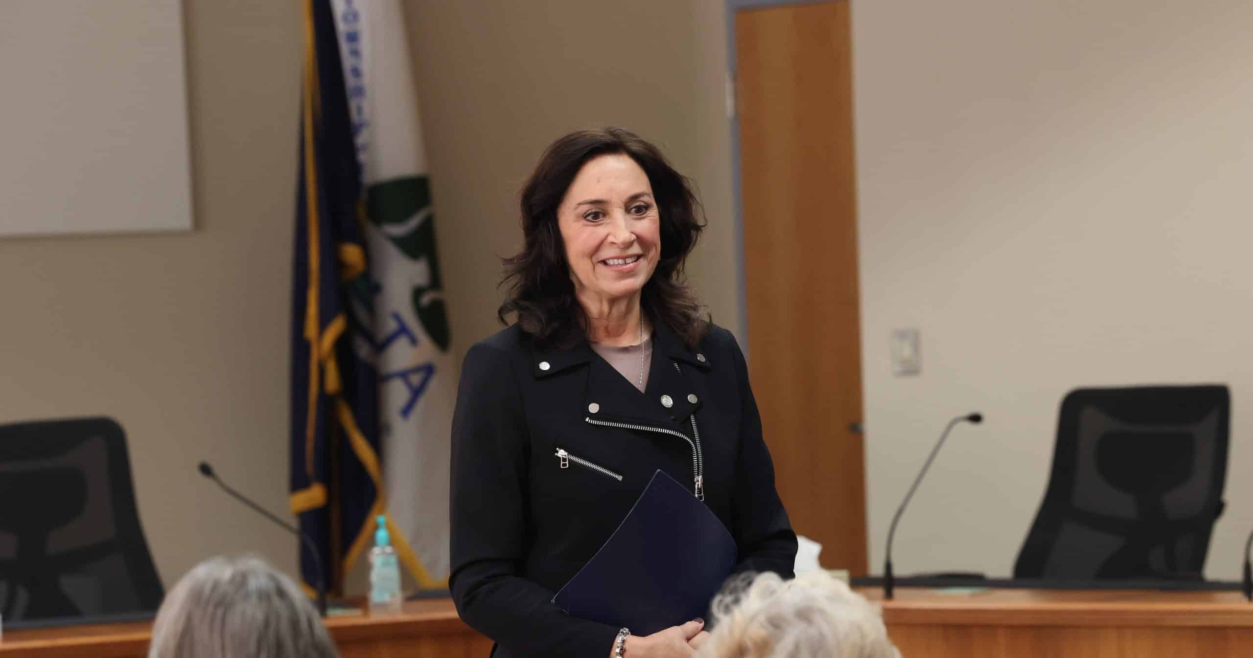 State Representative Angela Witwer speaking to a crowd of community members at a town hall meeting.