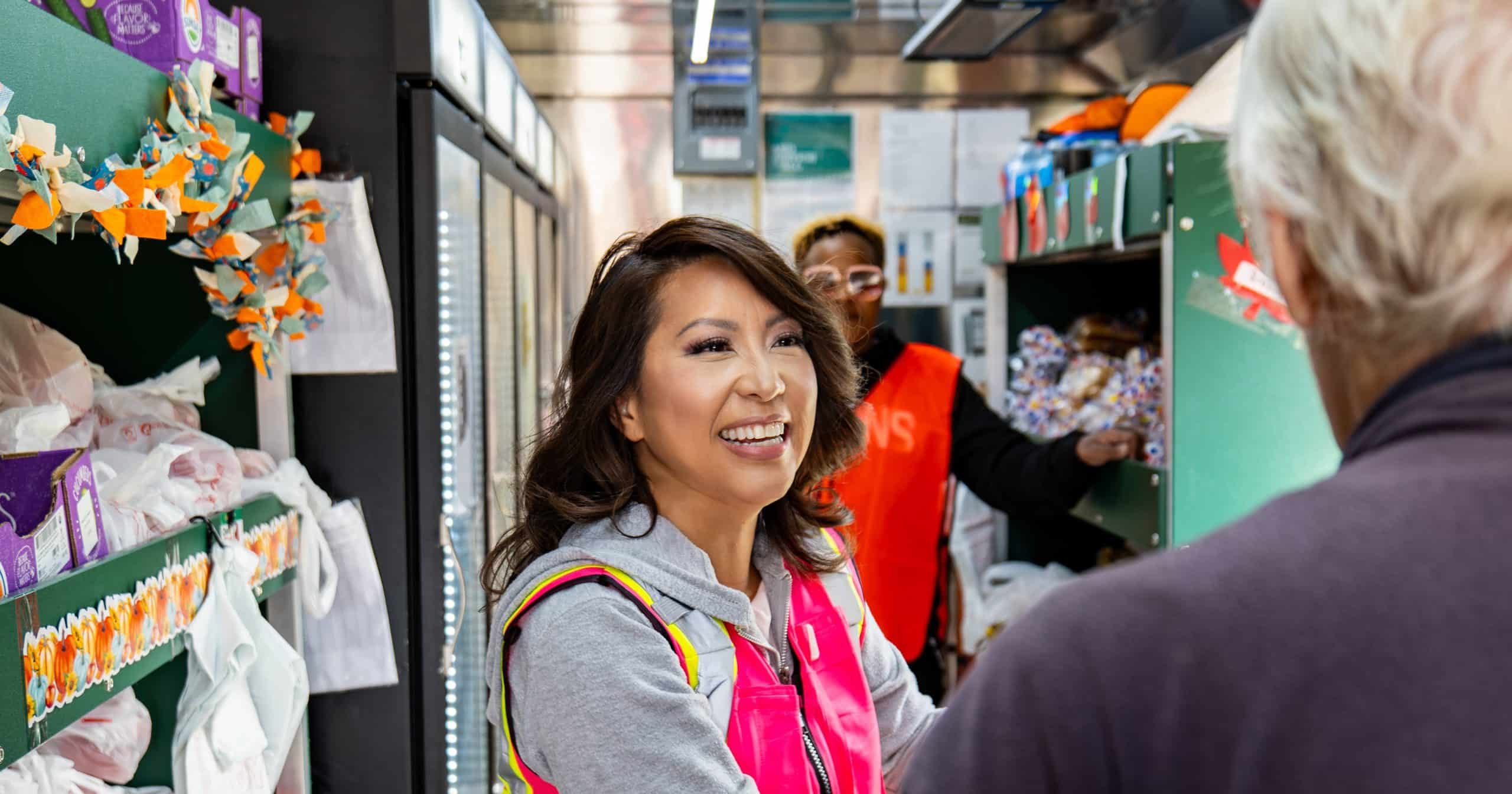State Representative Mai Xiong speaking with a community member while helping pass out meals in the Forgotten Harvest Mobile Food Truck parked in Roseville.